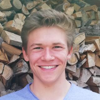 Blonde guy in front of wood.